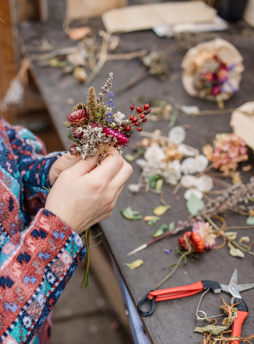 Hände binden einen Trockenblumenstrauß