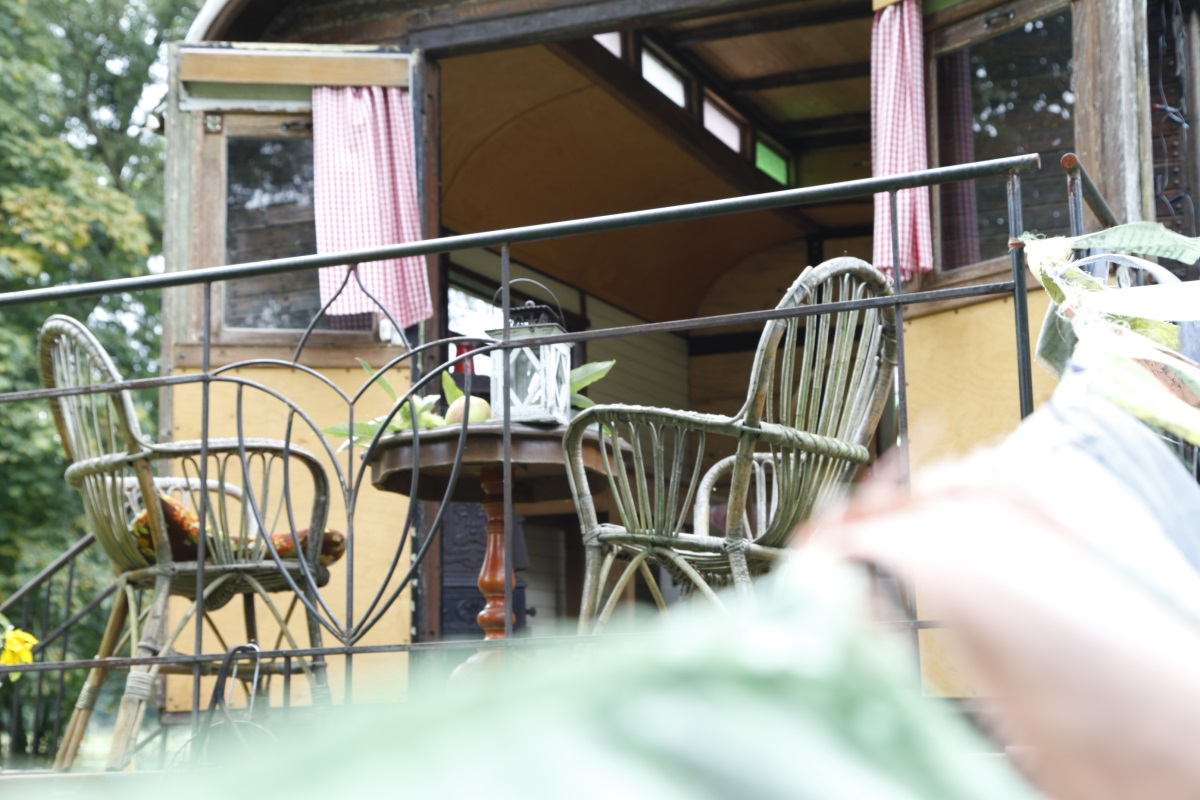 Veranda mit zwei Korbsesseln, kleinem Tisch und Laterne vor dem Wagen